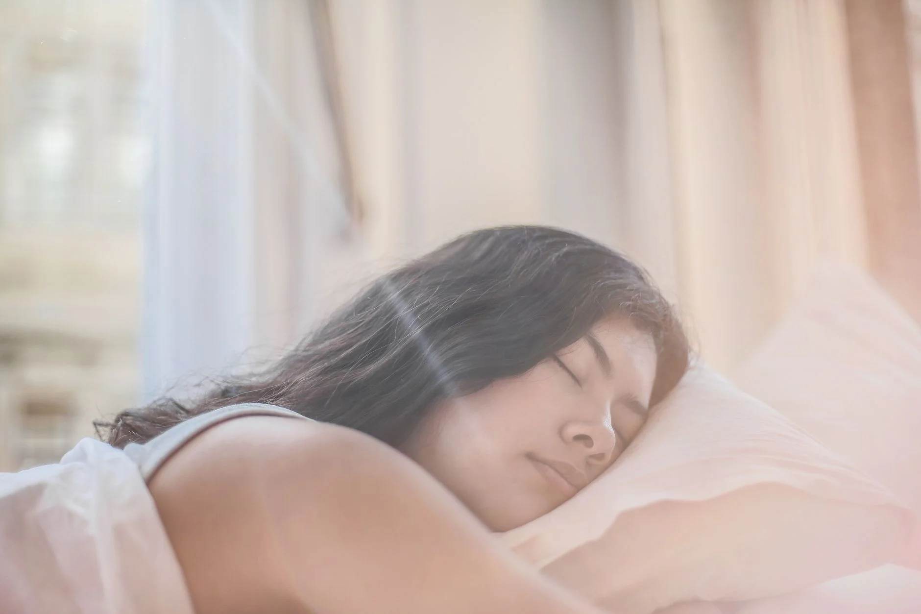 A woman sleeping peacefully on a pillow in soft morning light