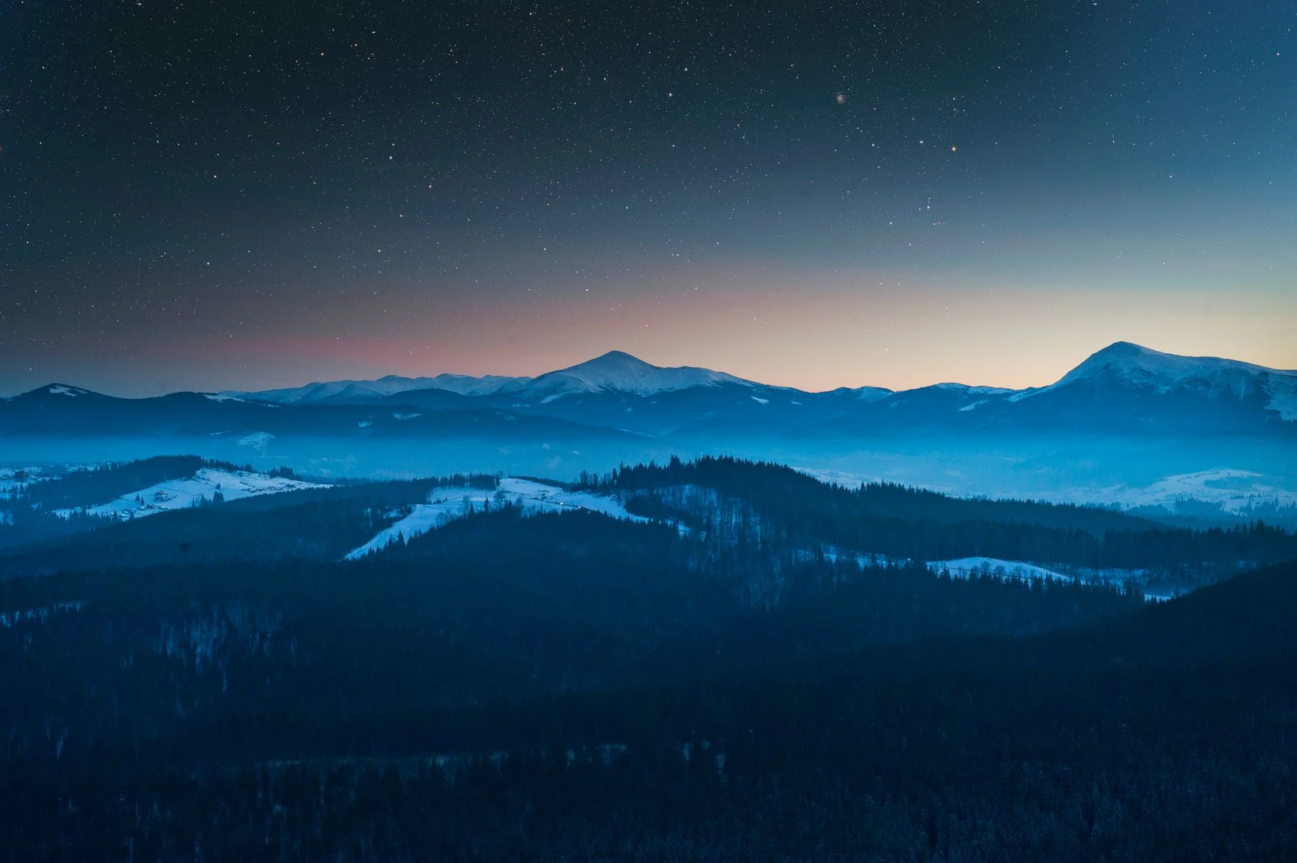 Snowy mountains under a starry twilight sky
