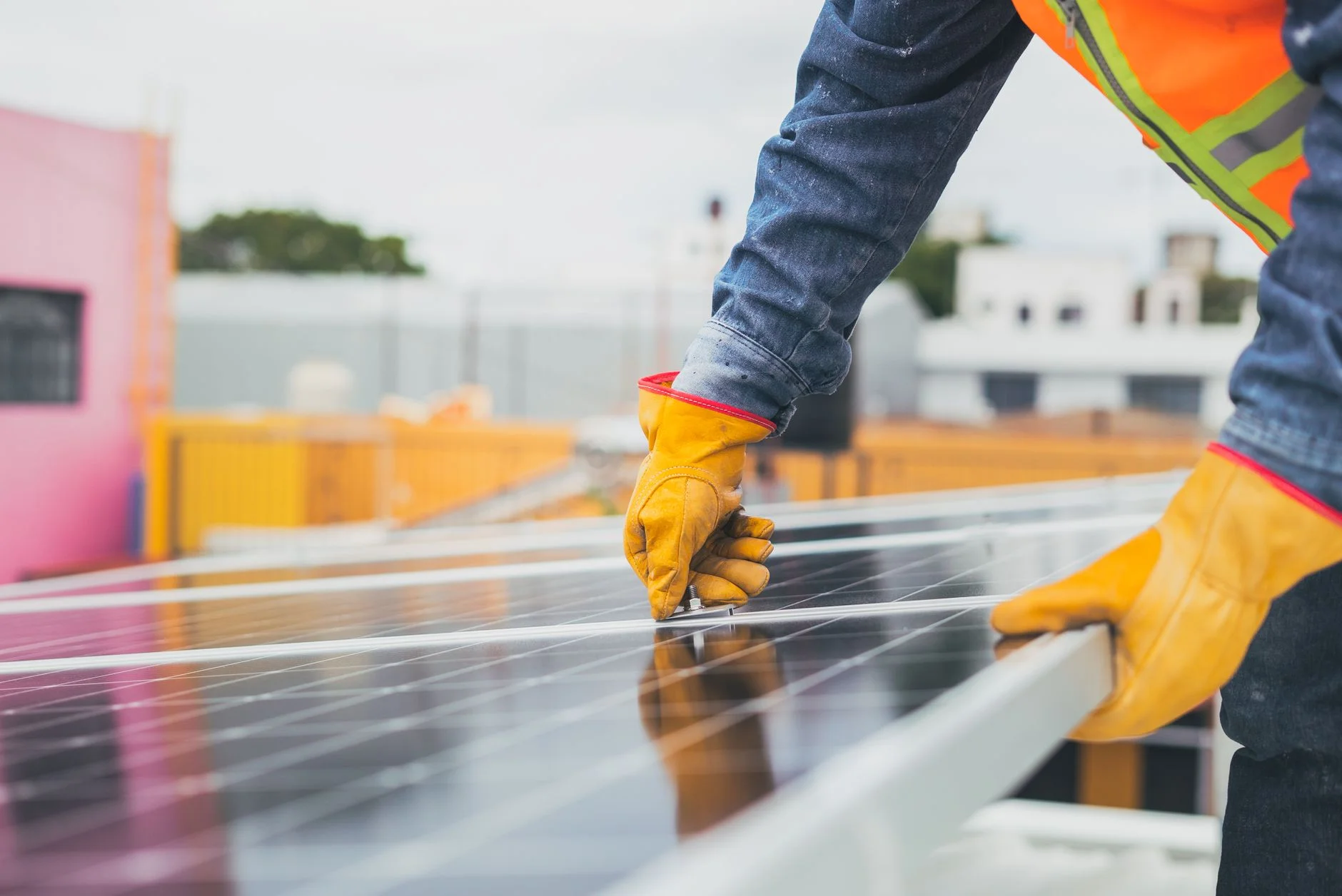 Technician in gloves and hi-vis checking the frame of a solar panel