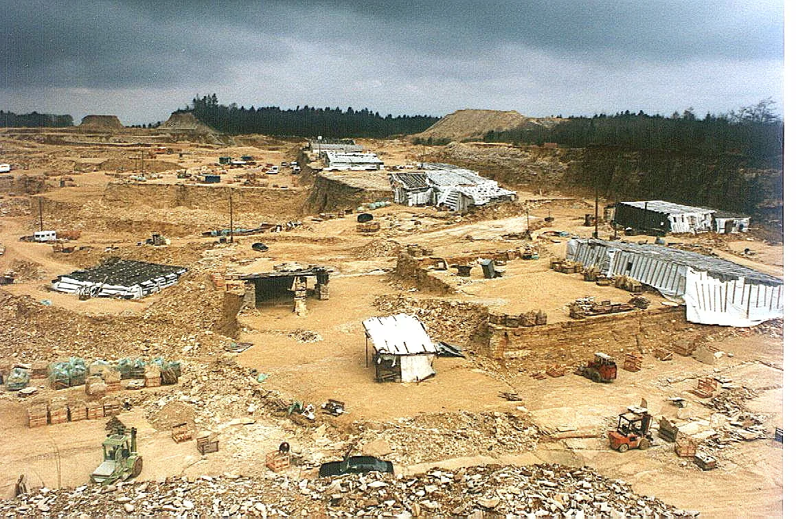 A limestone quarry near Solnhofen in Bavaria with white buildings and spoil heaps under a cloudy sky