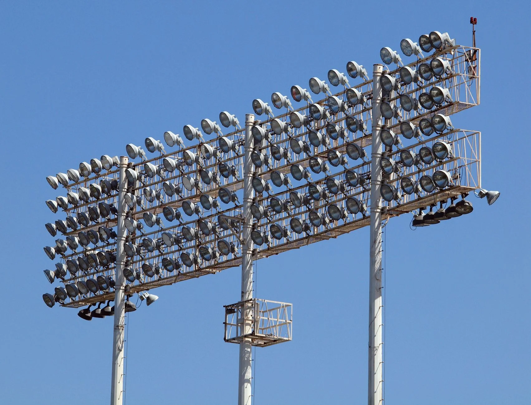 Banks of stadium floodlights against a blue sky