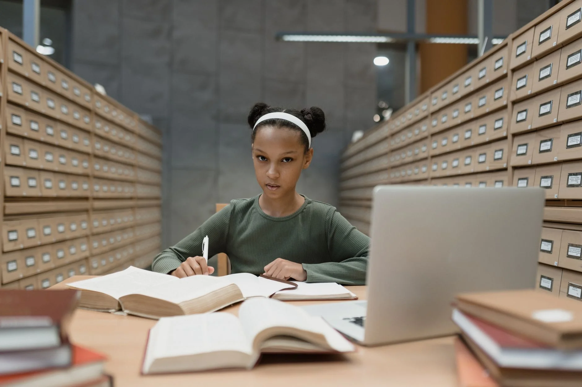 A student researching in a library with books and a laptop