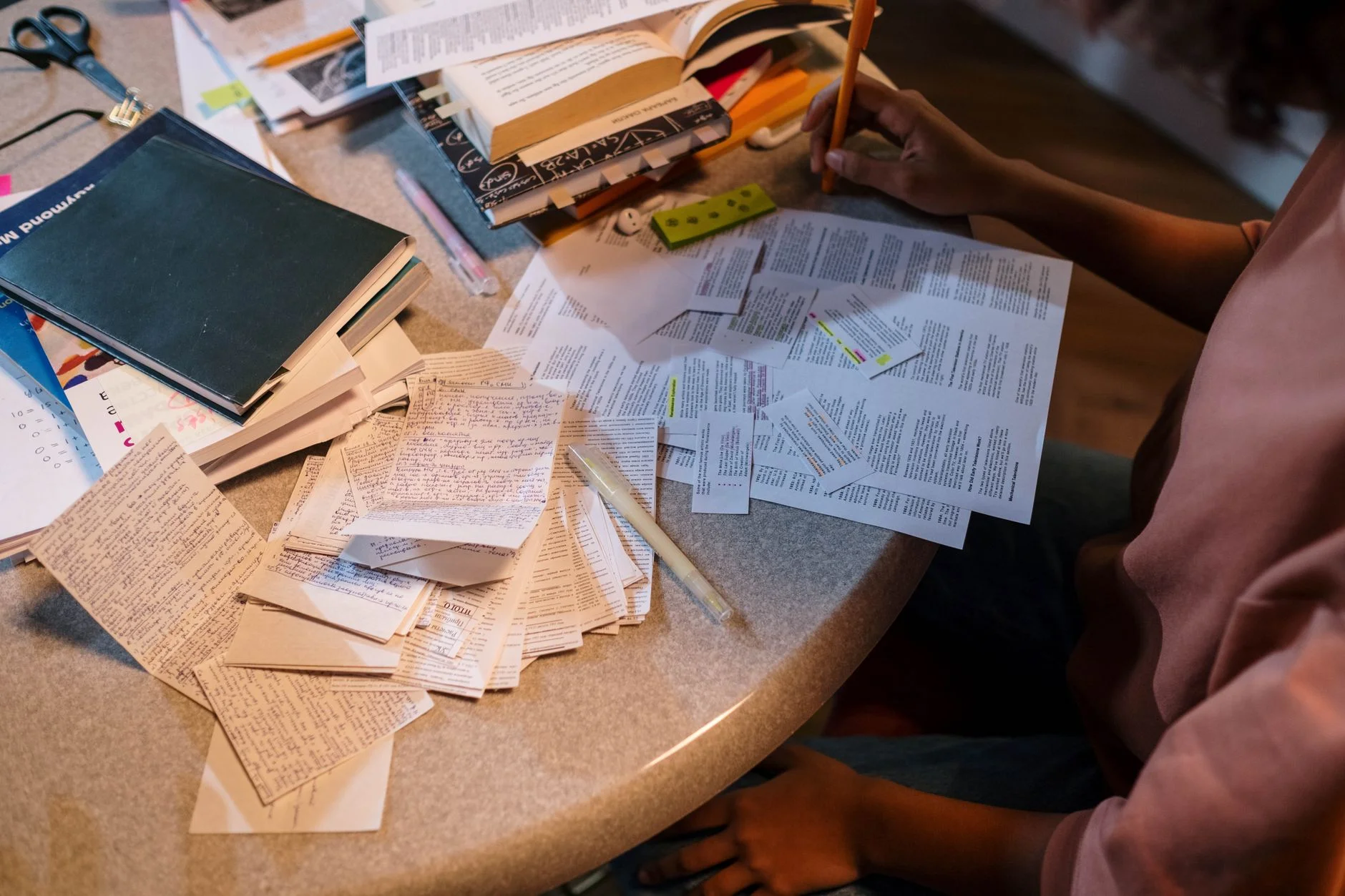 A student arranging colourful revision notes and sticky notes on a desk