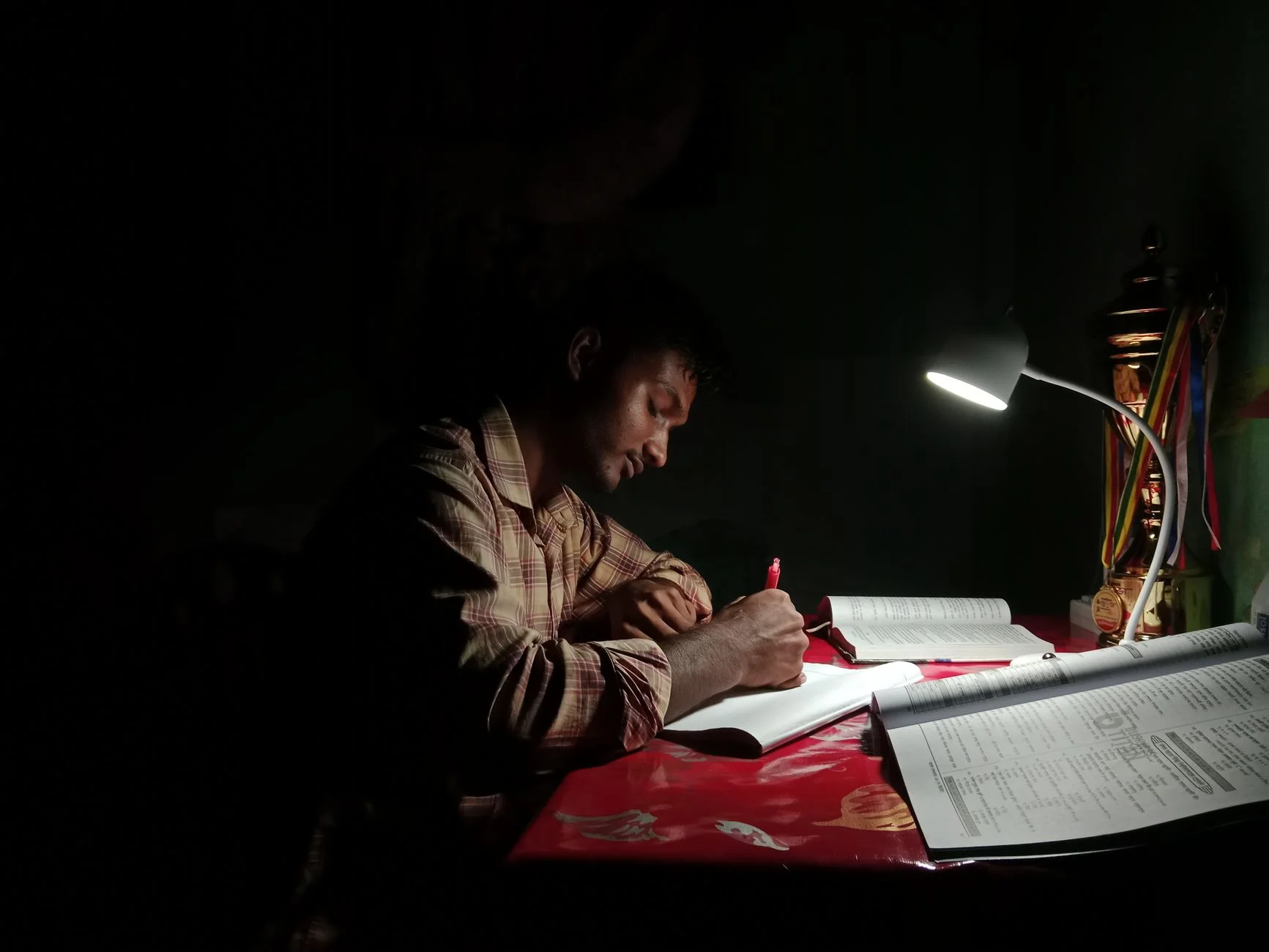 A student studying at a desk under a lamp in the evening
