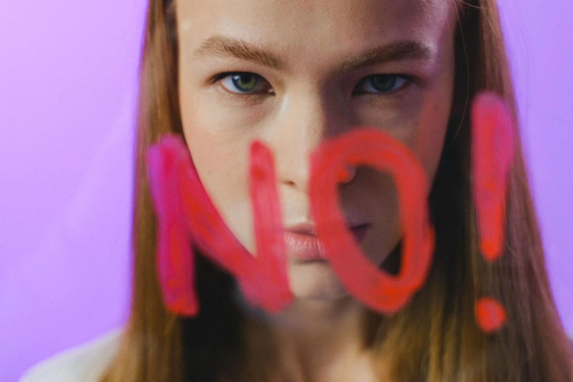 A teenage girl with the word NO written in red on glass in front of her face