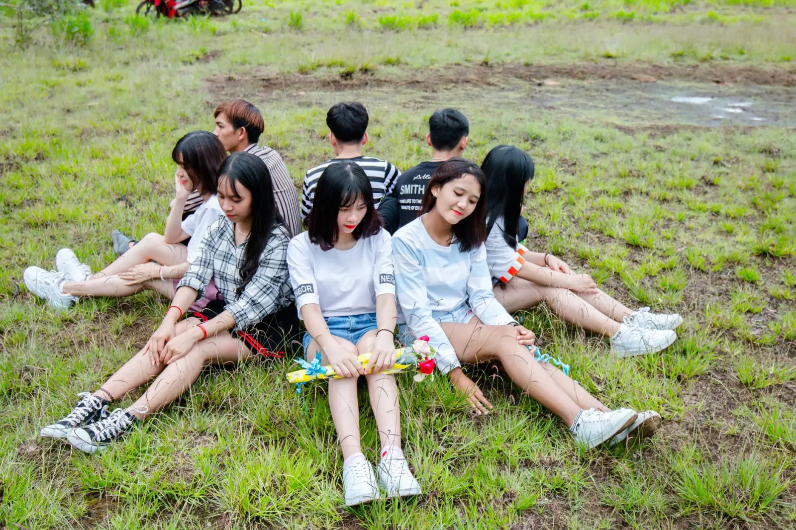 A group of teenagers sitting together on the grass on a sunny day