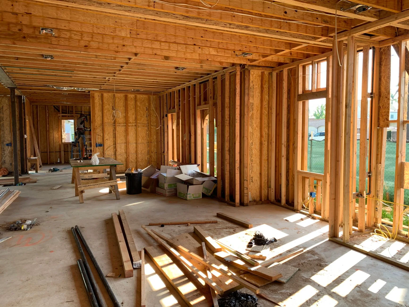 Interior of a house under construction with a bare timber stud frame, windows and open floor