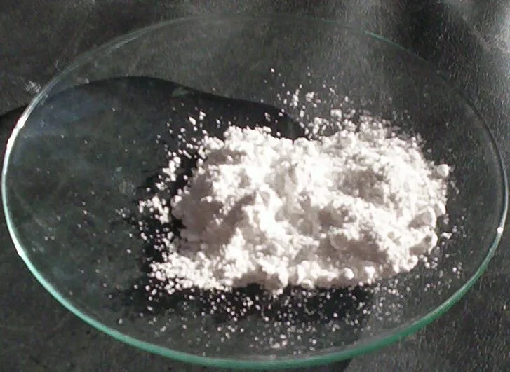 A small heap of white titanium dioxide powder on a glass watch glass