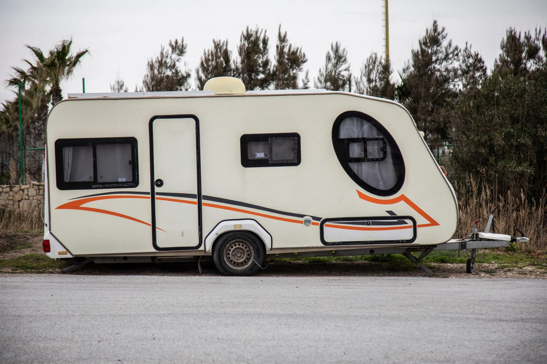 A single-axle touring caravan parked on a roadside with its A-frame and jockey wheel at the front
