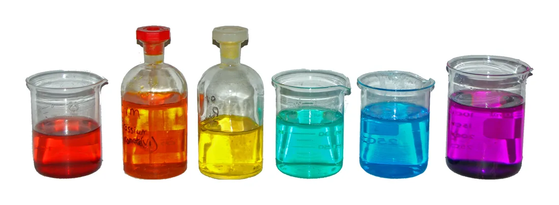 A row of coloured solutions in beakers and bottles: red, orange, yellow, green, blue and, at the end, purple potassium permanganate