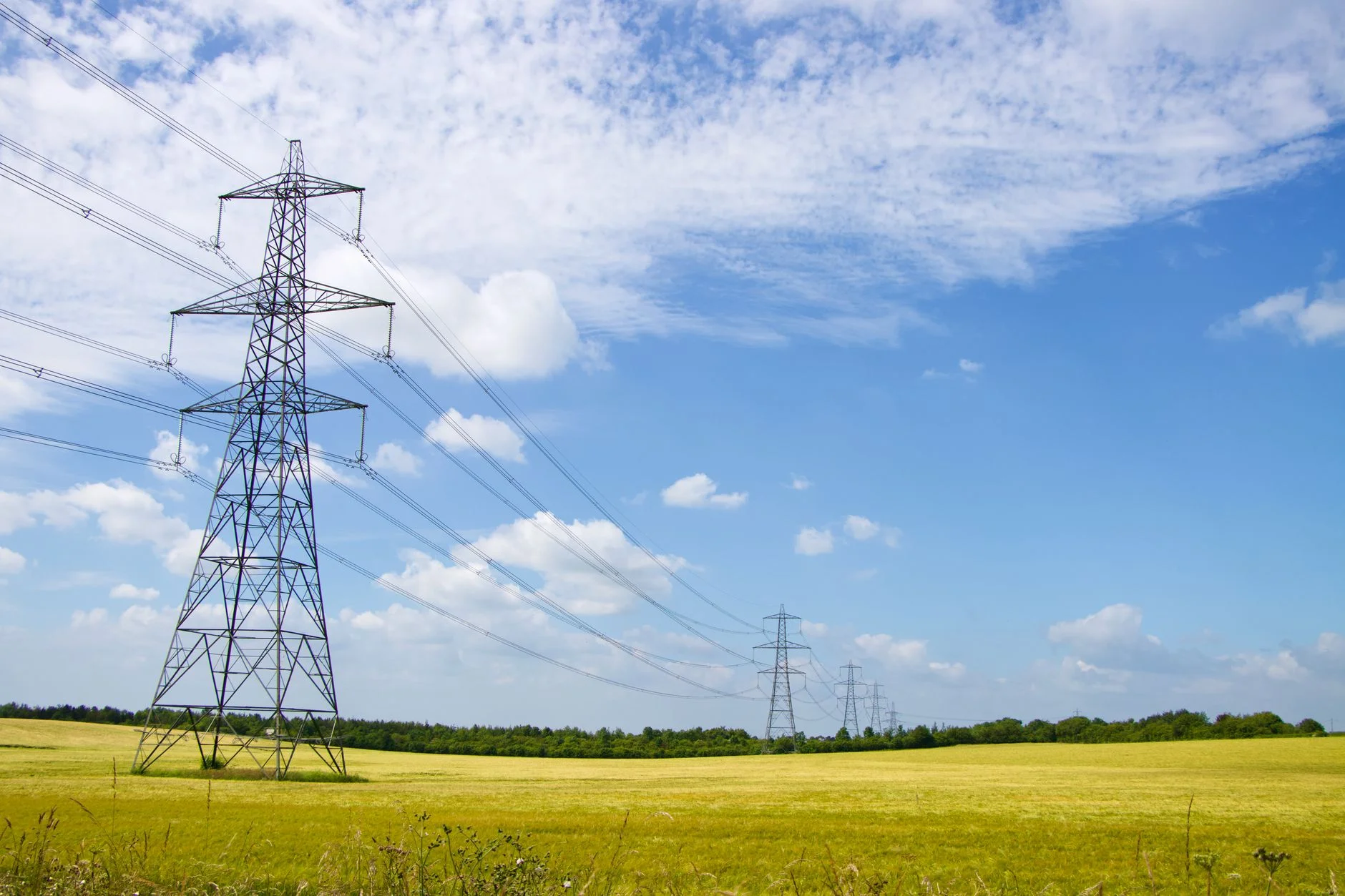 Steel lattice electricity pylons carrying high voltage lines across a field in England