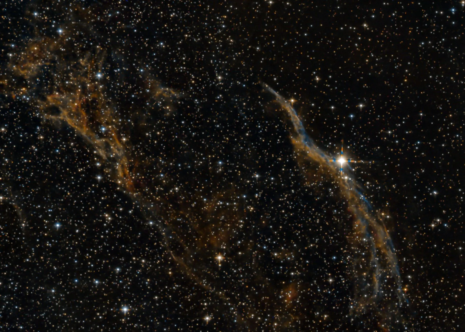 The Veil Nebula, the glowing wisps of a supernova remnant among thousands of stars