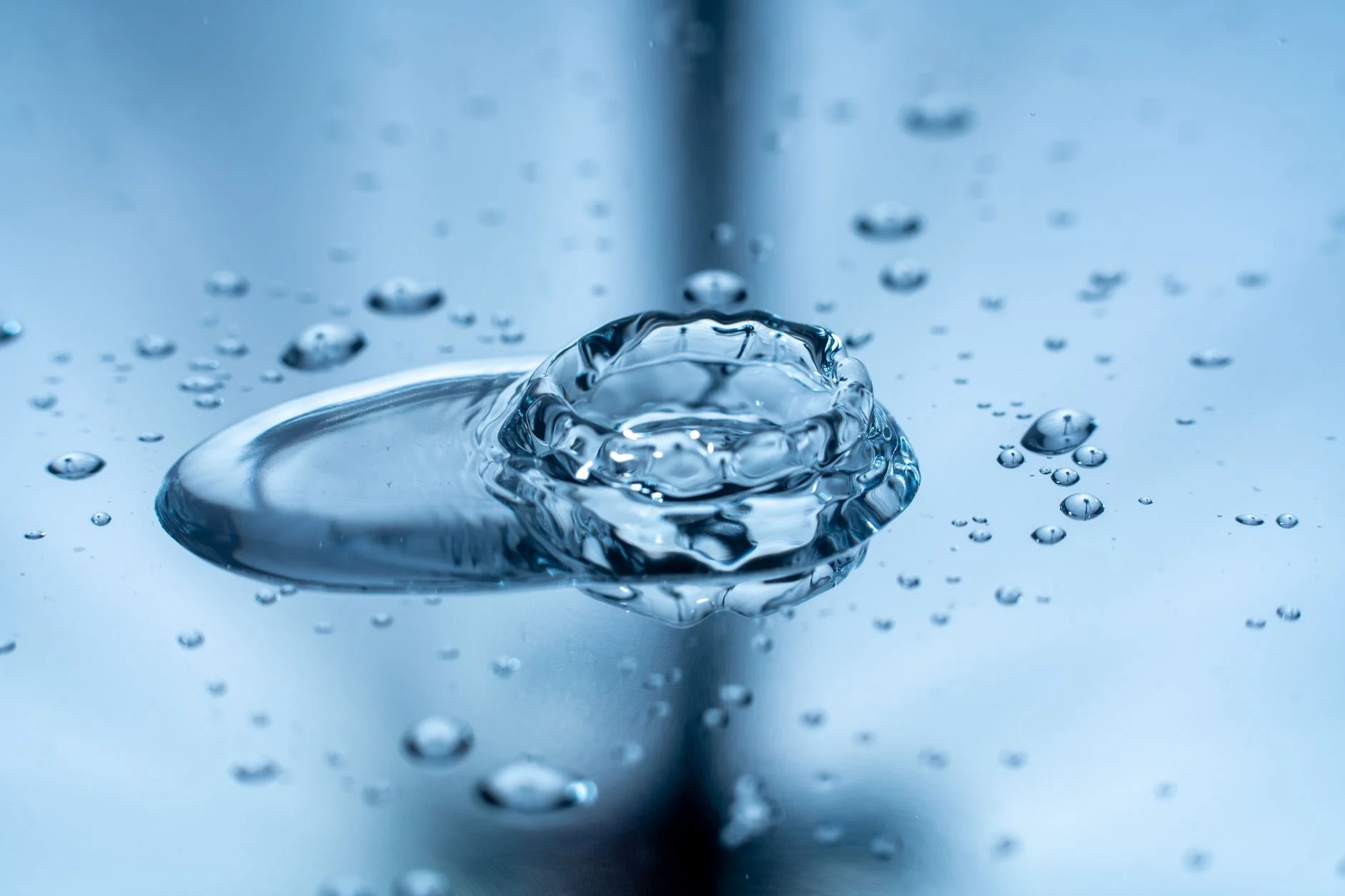 A drop of water splashing on a clear surface with tiny droplets around it