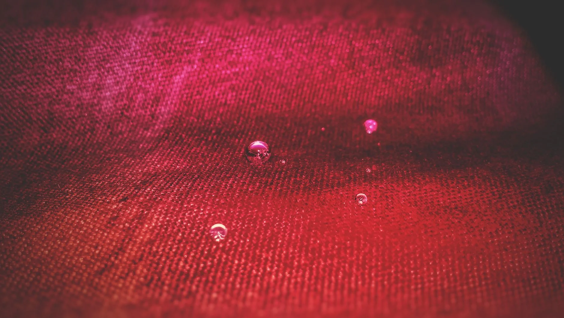 Round water droplets sitting on top of a water-repellent fabric surface